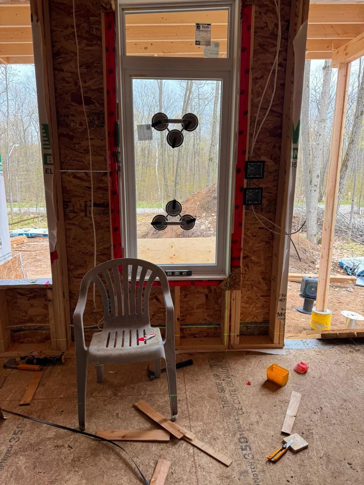Interior view of tall new construction window being levelled and supported