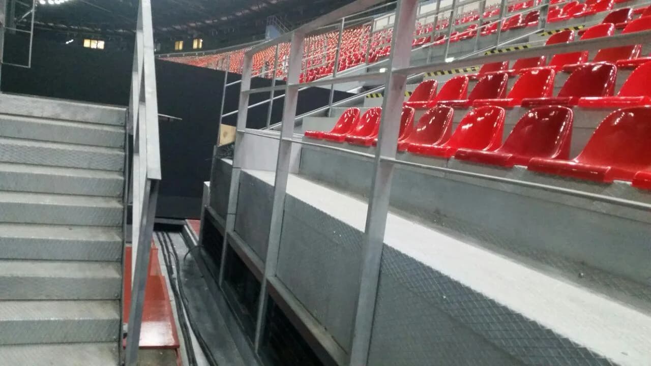 Aluminum grandstand stairway and guardrails beside red spectator seats